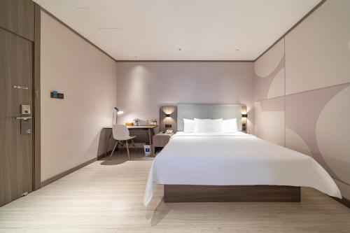 une chambre avec un grand lit blanc et un bureau dans l'établissement Hanting Hotel Shanghai Jiaotong University Jiangchuan Road Subway Station 2, à Shanghai