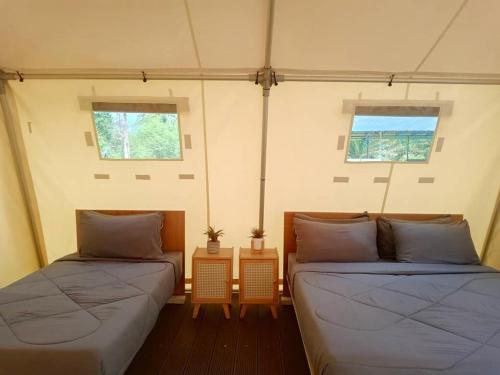 two beds in a room with two windows at Hilir Hening Glamping in Batu Caves