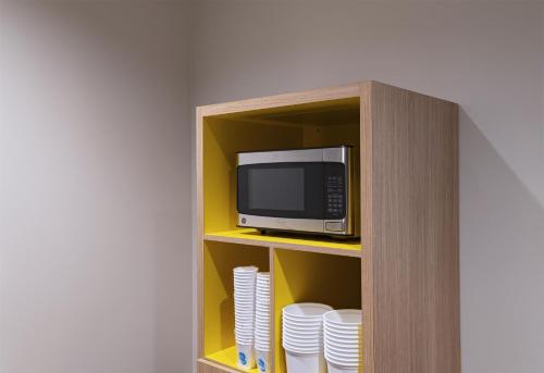 a cabinet with a microwave and plates in it at Tru By Hilton Irving Dfw South in Irving