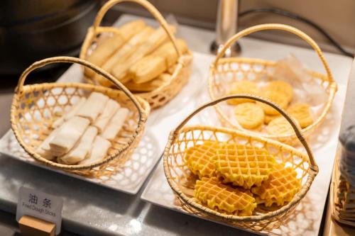 trois paniers de pain et de bananes sur un comptoir dans l'établissement Hanting Hotel Shanghai Jiaotong University Jiangchuan Road Subway Station 2, à Shanghai
