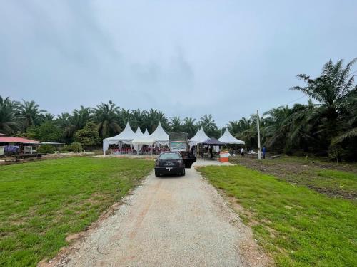 Un coche circulando por un camino de tierra con tiendas de campaña blancas. en Nizana House Homestay, en Batu Pahat