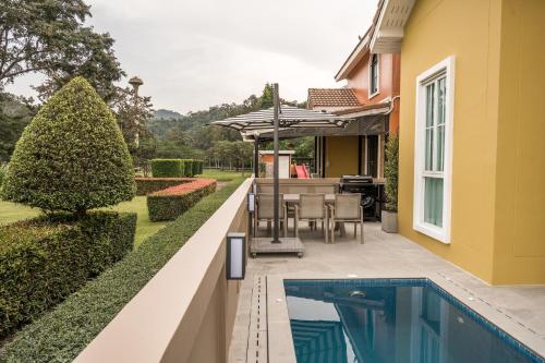 Casa Margarita Khao Yai في Nong Nam Daeng: حديقة خلفية مع حمام سباحة ومنزل