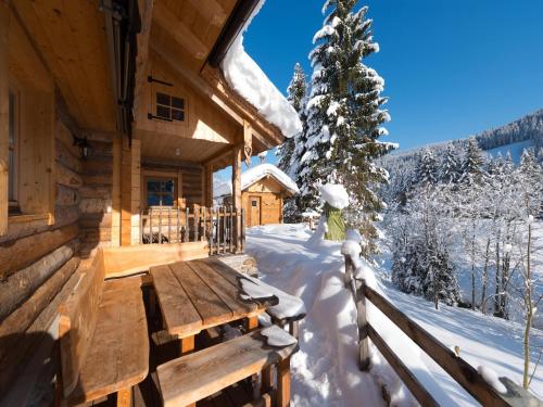 a wooden cabin in the snow with a wooden bench at Chalet Steinbock, St Martin am Tennengebirge in Sankt Martin am Tennengebirge