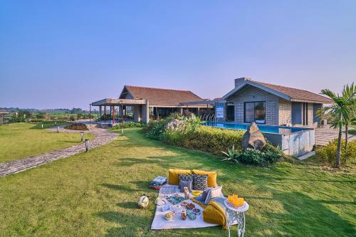a couch on the grass in front of a house at SaffronStays Ashfield - 5BHK Eco-Farmhouse with Pools, Jacuzzi, Lawn & Games Room in Nashik