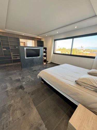 a bedroom with a large bed and a flat screen tv at Prestige home in Et Tnine Oudaya