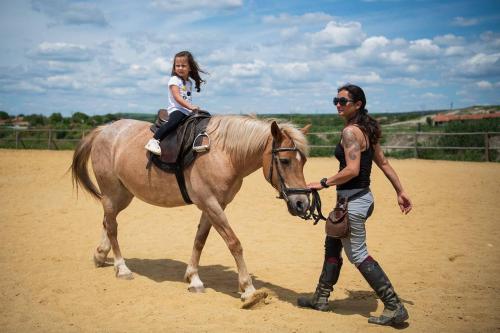 a woman leading a girl on a horse at Вила Вяра, Надежда, Любов in Neofit Rilski
