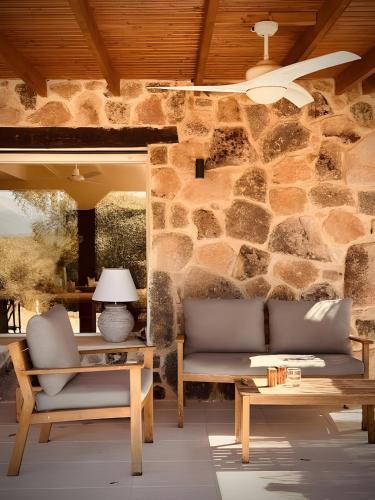 Casa en el Valle del Tietar CR-AV-01516 في Fresnedillas: غرفة معيشة مع كرسيين وجدار حجري