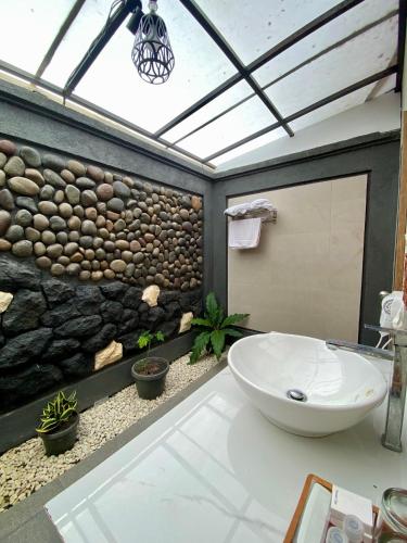 a bathroom with a sink and a stone wall at Omnni Villa Borobudur in Borobudur