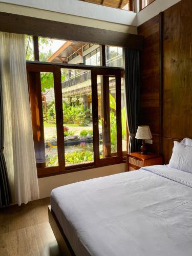 a bedroom with a bed and a large window at Omnni Villa Borobudur in Borobudur