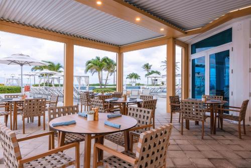 an outdoor patio with tables and chairs and windows at Beach House Fort Lauderdale, A Hilton Resort in Fort Lauderdale