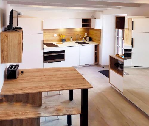 a kitchen with white cabinets and a wooden table at Le refuge du prieuré - Les Gîtes de la Côte d'Amour in Batz-sur-Mer