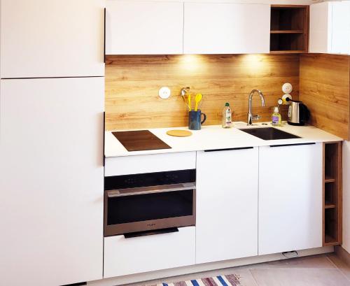 a kitchen with white cabinets and a sink at Le refuge du prieuré - Les Gîtes de la Côte d'Amour in Batz-sur-Mer