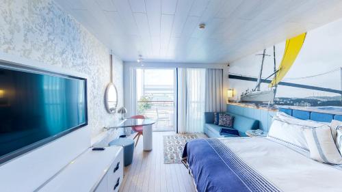 Karpaz Gate Marina Hotel في Ayia Trias: غرفة نوم مع تلفزيون بشاشة مسطحة كبيرة وسرير