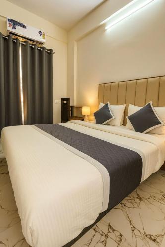 a bedroom with a large white bed with blue pillows at Hotel Stay Bliss Marathahalli in Bangalore