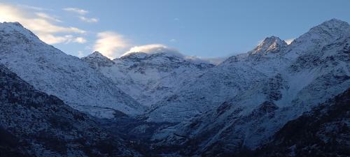 a snow covered mountain range with clouds in the sky at Atlas Pearl lodge in Imlil