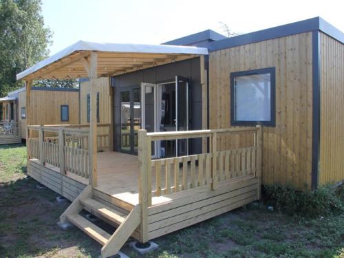 a wooden cabin with a porch and a deck at Modern 6-person chalet in the Frisian countryside, 3 bedrooms and WiFi in De Veenhoop