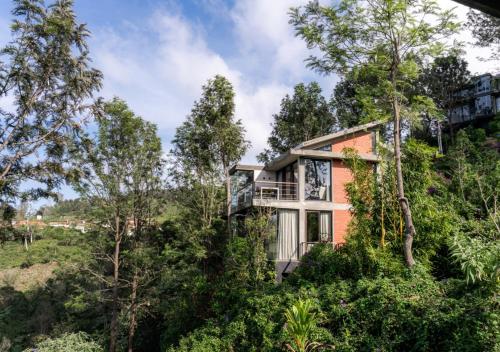 ein Haus an der Seite eines Hügels mit Bäumen in der Unterkunft LohonoStays Amani Villa 9B in Coonoor