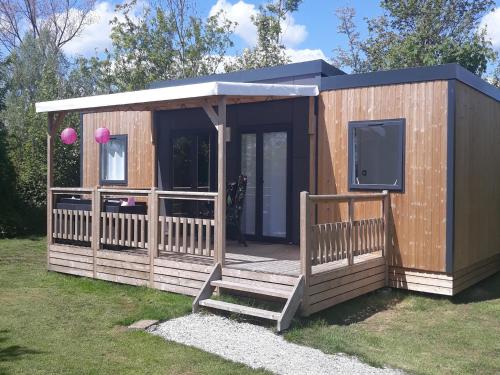 a wooden cabin with a tv and a porch at Modern 6-person chalet in the Frisian countryside, 3 bedrooms and WiFi in De Veenhoop