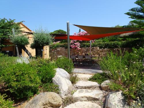 a garden with a table and a red umbrella at Les Voiles in Pinarellu