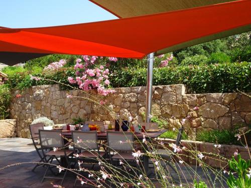 a table with a red umbrella in a garden at Les Voiles in Pinarellu
