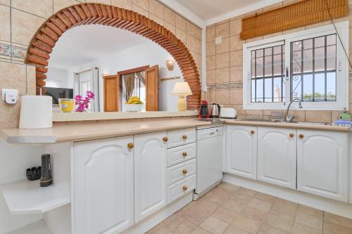 una cucina con armadi bianchi e un arco di Villa Grayce a Frigiliana