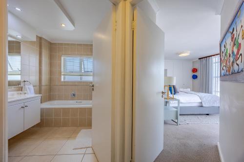 a bathroom with a tub and a bedroom with a bed at Luxury Ocean View Beachfront 2 bed apartment -206 The Waves, Blouberg, Cape Town in Bloubergstrand