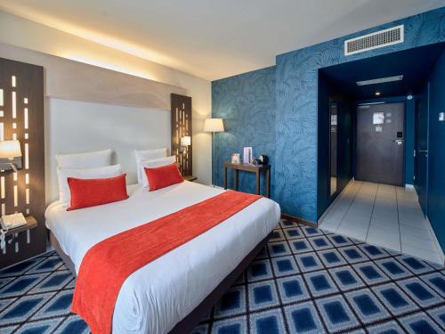 a hotel room with a large bed with red pillows at Mercure Chartres Centre Cathedrale in Chartres
