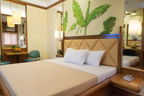 a hotel room with a bed and a desk at Kabayan Hotel Pasay in Manila