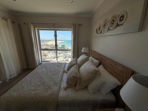 a bedroom with a bed with a large window at Beachfront Luxury Apartment Sea View & Free Parking in Gqeberha