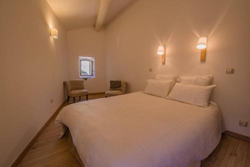a bedroom with a large white bed and two chairs at Spacieux Duplex - Lumineux et Calme - Alpilles in Eyguières