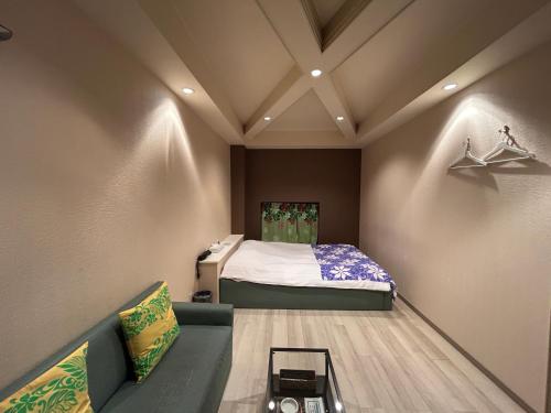a small room with a bed and a couch at Hotel Maile in Tokyo