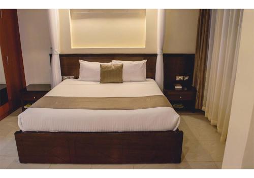 Un dormitorio con una cama grande en una habitación de hotel. en The Pinecone Hotel Kisumu, en Kisumu