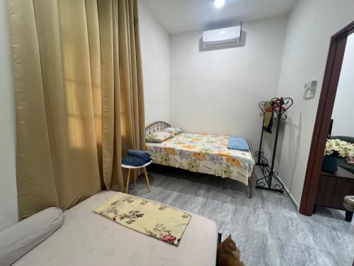 een kleine kamer met 2 bedden en een stoel bij DGarden Homestay in Kuala Terengganu