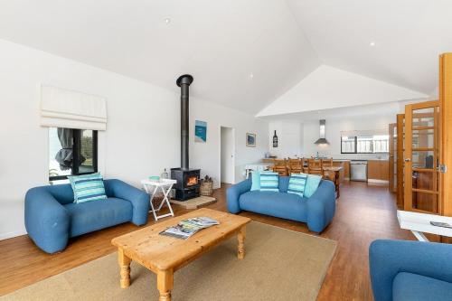 ein Wohnzimmer mit 2 blauen Stühlen und einem Tisch in der Unterkunft Beachfront Prevelly Exclusive Holiday Home in Prevelly