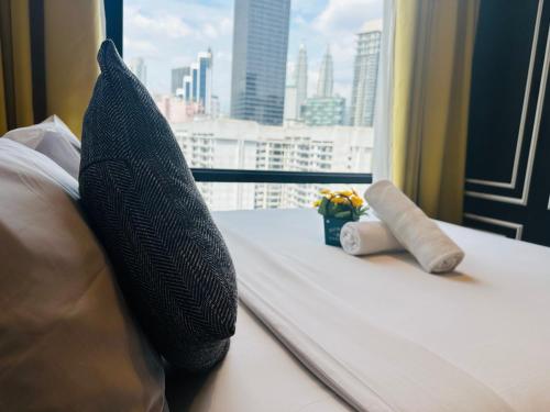 a bed with pillows and a view of a city at Bukit Bintang Suites KL in Kuala Lumpur