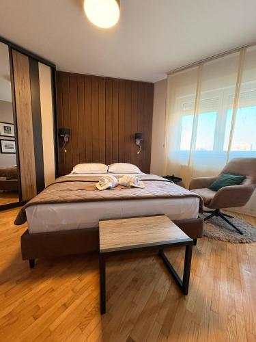 a bedroom with a large bed and a chair at NAR Royalton Deluxe Apartment #74 in Niš