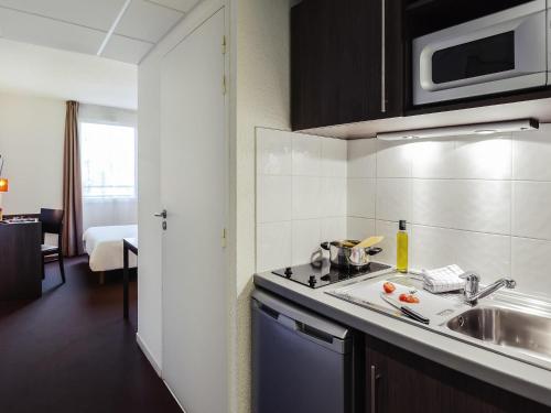 a small kitchen with a sink and a microwave at Aparthotel Adagio Access Orléans in Orléans