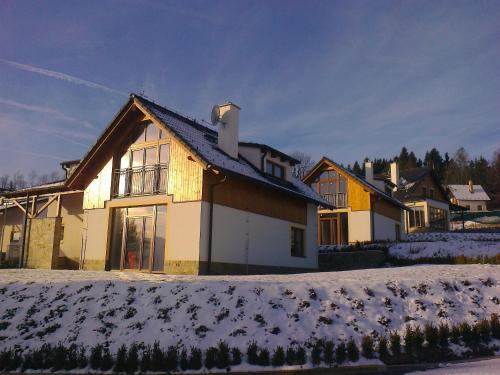 a house with snow on the ground in front of it at Residence Lipno in Lipno nad Vltavou