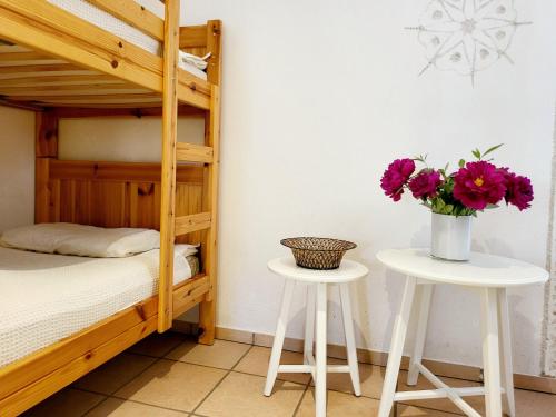 a bedroom with a bunk bed and two tables with flowers at Schöne Gartenwohnung am Strand von Tegna Centovalli in Tegna