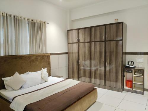 a bedroom with a large bed with a wooden cabinet at Primrose Hotel in Murthal