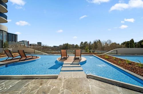 Modern & Stylish Haven Westfield Hospital, gym&Pool, Free P في Phillip: مسبح مع كراسي جلوس فوق المبنى