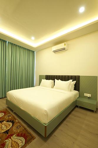 a bedroom with a large white bed with green curtains at Veerdency Luxury Resort - 3 Km to Banglore Airport in Bangalore