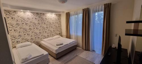 a bedroom with two beds and a large window at Del Monte Predeal in Predeal