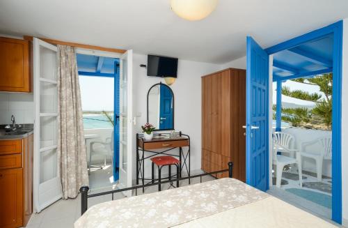 a bedroom with a blue door and a table with a chair at Diogenis Studios in Naxos Chora