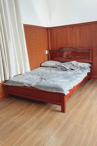 a bed with a wooden headboard in a bedroom at Phụng Kim Thảo Hotel Long An in Long An