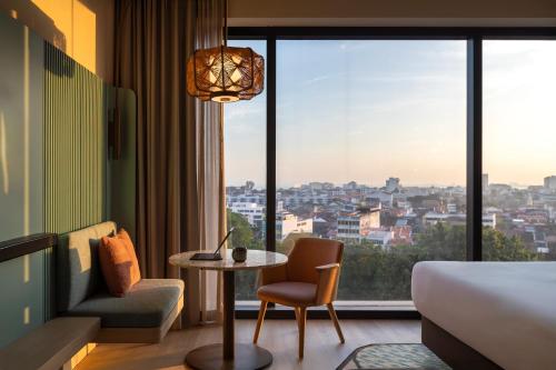 a hotel room with a bed and a table and a window at Capri by Fraser, Penang in George Town