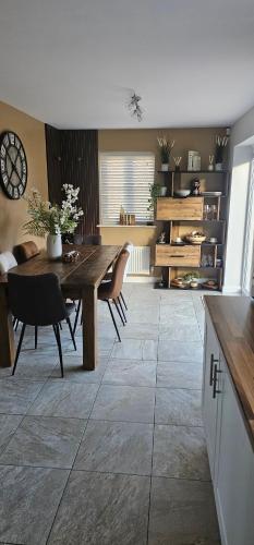 Hart's Place في Broughton Astley: غرفة طعام مع طاولة وكراسي وساعة