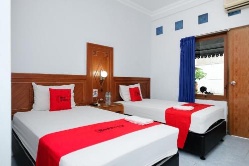 two beds in a hotel room with red accents at RedDoorz at Hotel Raditia Graha Yogyakarta in Yogyakarta