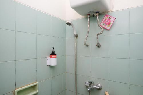 a shower in a bathroom with blue tiles at RedDoorz at Hotel Raditia Graha Yogyakarta in Yogyakarta
