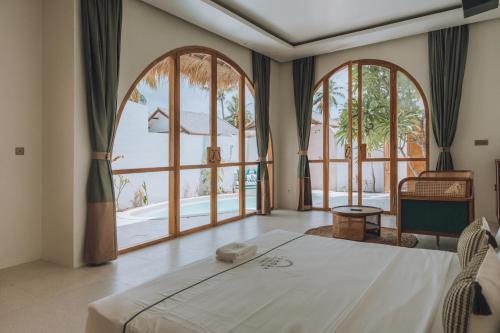 a bedroom with a large bed and large windows at Lumora Boutique Villas in Gili Trawangan